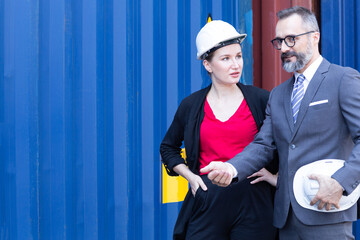 Smart creative logistics manager and Shipping engineer woman discussion, talking and check up control loading containers box from cargo freight ship for import export.  Logistics worldwide connect.