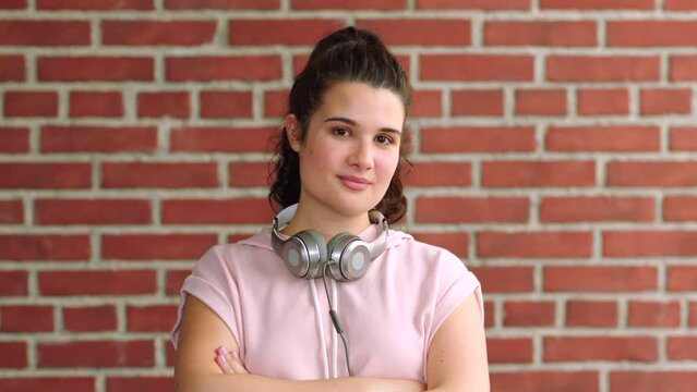 Portrait of a trendy confident woman against a red brick wall with copy space. Young confident student who enjoys listening to music as for leisure or during her study breaks on campus or university