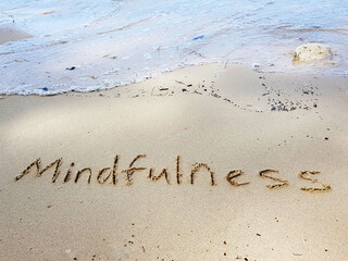 Mindfulness concept. The word Mindfulness written on sand.