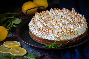 Lemon cake with protein cream, on a light background, with lemon slices and mint leaves.
