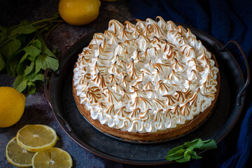 Lemon cake with protein cream, on a light background, with lemon slices and mint leaves.