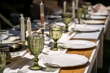 The table is set for a good party. The table is set. Empty plates and unusual glasses. vintage tray, candle holder and vases with beautiful flowers. Everything for a special day