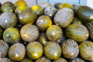 Piled Piel de Sapo melons for sale at a street fruit market