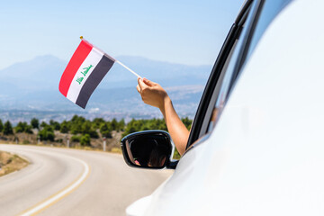 Woman holding Iraq flag from the open car window driving along the serpentine road in the...