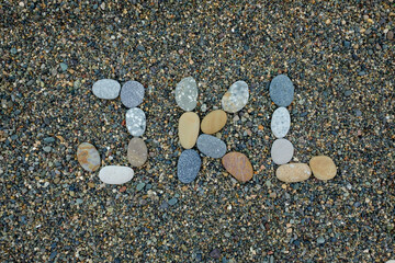 letters j k l made from stones in sand on beach