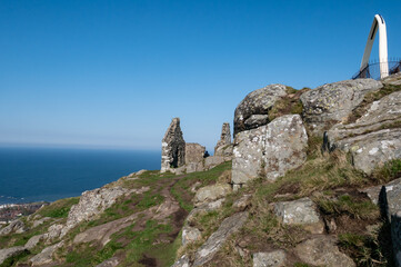 The top of North Berwick Law with rocks and ruins of a stone house on a clear blue day