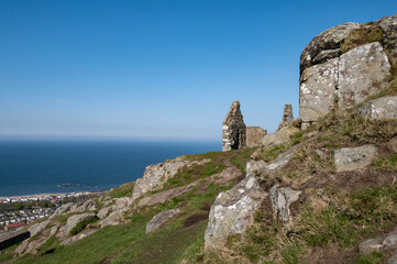 Fototapeta na wymiar The top of North Berwick Law with rocks and ruins of a stone house on a clear blue day