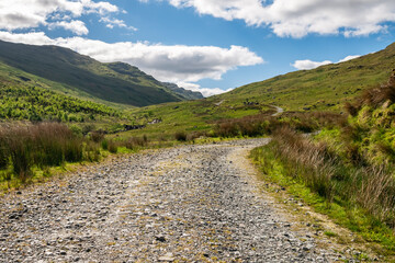 Fototapeta na wymiar Tourist path through beautiful green Scottish mountain scenery on a hot summer day in Scotland