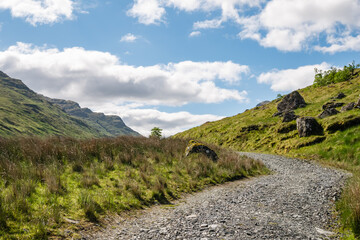 Fototapeta na wymiar Tourist path through beautiful green Scottish mountain scenery on a hot summer day in Scotland