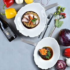 Meat dishes, wine and vegetables on a gray table. Pork belly and beef cheeks. Italian food. Background. Top view