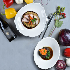 Meat dishes, wine and vegetables on a gray table. Pork belly and beef cheeks. Italian food. Background. Top view