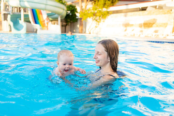 mom and baby in the pool with water slides in the summer have fun swimming, relaxing and spending time with the family