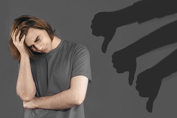 Bullying concept with silhouette thumb down. Sad young man. The guy keeps his hand on his head,...