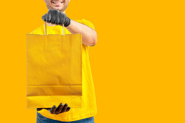 Delivery man with paper bag. Courier in uniform t-shirt, gloves service fast delivering orders....