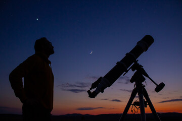 Man with astronomical telescope observing night sky, under the Milky way stars.