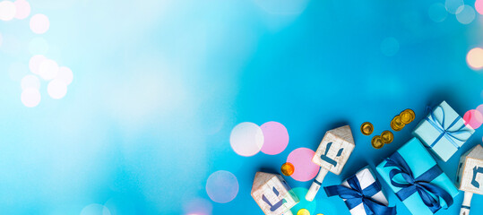 Dreidel, dreidle or dreidl with blue lettering on bright background. Gift box, spinning top, Jewish...