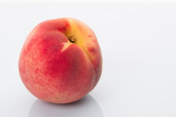 A bright red peach on a white background