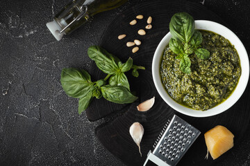 Ingredients for pesto sauce in the white bowl. Green basil leaves, Parmesan cheese and pine nuts on...