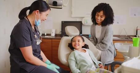 Dentist and child giving high five during fun dental appointment. Mom clapping for daughter after completed checkup to prevent tooth decay and gum disease. Learning about oral and dental hygiene
