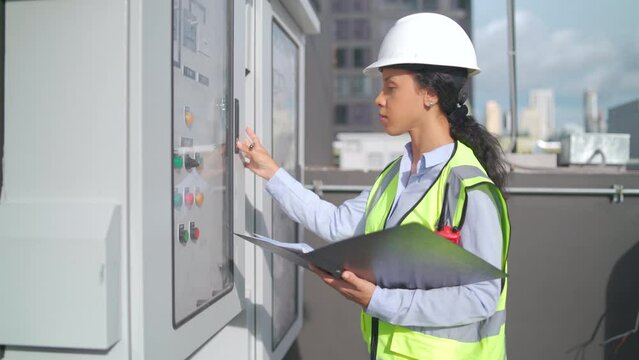 Engineer woman or technician worker check or maintenance electricity control panel in area of rooftop of construction site.
