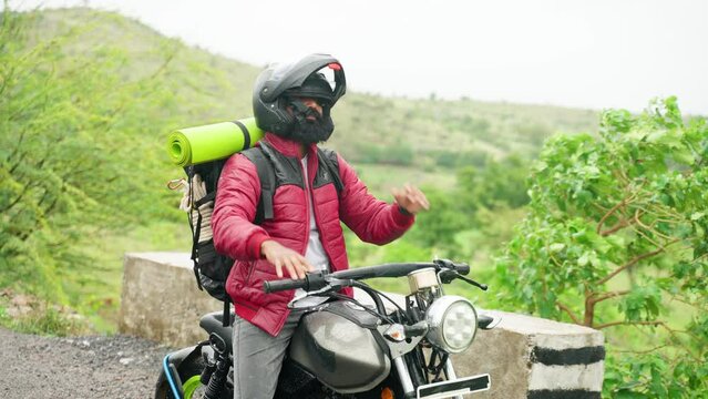 Beard man with jacket wearing helmet before riding on motorbike at mountain - concept of adventure, safe journey and weekend holidays