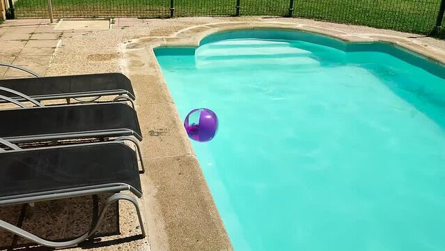 blue summer swimming pool with floating feather stuffed beach ball, lounge chairs around and natural grass - paradise vacation background without people for a calm scene