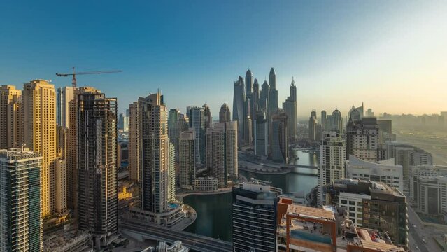 Panorama of various skyscrapers in tallest recidential block in Dubai Marina aerial timelapse during all day with artificial canal. Many yachts and towers with shadows moving fast