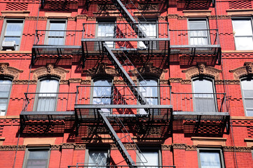A metal fire escape on the exterior of a red brick building in manhattan in new york city.