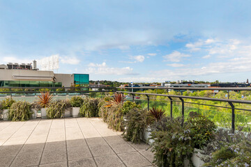 Fototapeta premium Terrace of an office building full of plants on a sunny day with some clouds