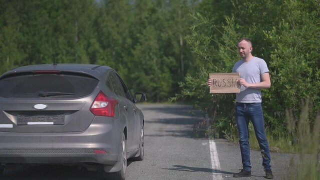 a man catches a passing car, the sign says Russia