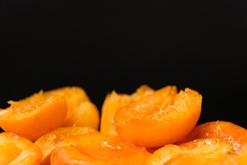 Juicy apricot slices on a black background, side view, space for text.