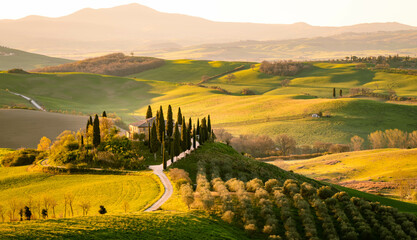 San Quirico d& 39 Orcia, Provinz Siena, Toskana, Italien. Bauernhaus zwischen toskanischen Hügeln während der Erntezeit.