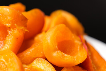 Juicy apricot slices on a black background, side view.