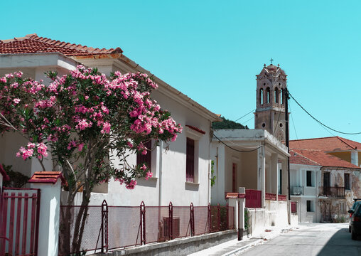  view in town of Ithaka in Greece, white house with red roof and windows, church in end of street