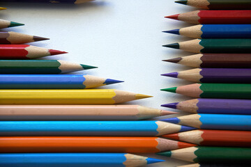 Colored pencils for drawing and coloring, on a white background. Figures made of colored pencils, stationery, school supplies