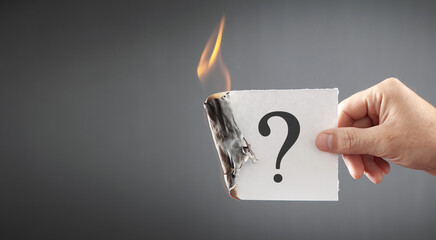 Fototapeta Male hand showing burning paper with a question mark. obraz