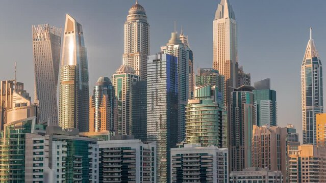 Dubai marina tallest block of skyscrapers timelapse during sunset. Aerial view from JLT district to apartment buildings, hotels and office towers near highway.