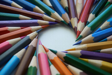 Fototapeta premium Colored pencils for drawing and coloring, on a white background. Figures made of colored pencils, stationery, school supplies