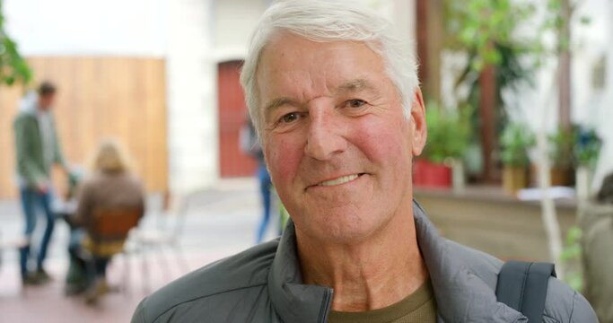 Portrait of happy senior man standing in a mall. Mature college professor at college or a tourist exploring a city. Face of grey haired male smiling and feeling confident while looking at the camera