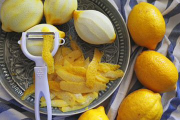 Lemon fruits and peeled strips for zest or making limoncello. Peeler, lemons and zest. Copy space,...