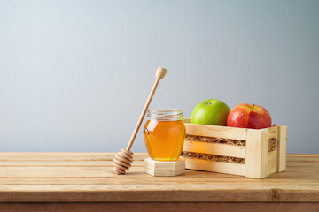 Fresh colorful apples in wooden box and honey jar on table. Greeting card background for Rosh...