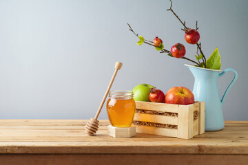 Still life composition for Rosh Hashanah holiday. Honey jar and apples in wooden box on table background