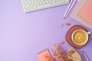 Stylish feminine table with coffee cup, notebook and computer keyboard over purple background. Back to school concept