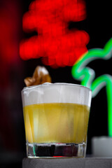 A cocktail with ice, foam and a leaf