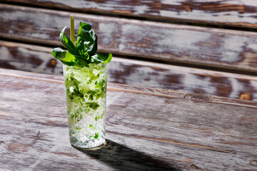 Cocktail with basil, ice and a straw