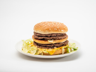 白い皿の上に乗った、たっぷりのビーフのパテとチーズを挟んだハンバーガー