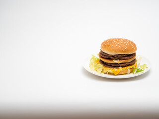 白い皿の上に乗った、たっぷりのビーフのパテとチーズを挟んだハンバーガー