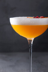 A cocktail with ice, orange, peppercorns and foam