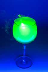 Smoky cocktail with a green laser, on a dark background. Dangerous liquor mixture - close up photo. Background picture. Selective focus.