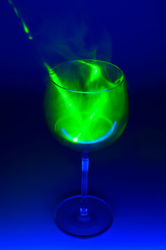 Smoky cocktail with a green laser, on a dark background. Dangerous liquor mixture - close up photo. Background picture. Selective focus.